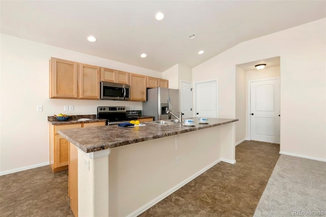 kitchen featuring lofted ceiling, a kitchen island with sink, a sink, baseboards, and appliances with stainless steel finishes