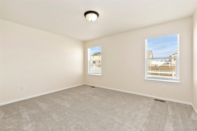 spare room with carpet, visible vents, and baseboards