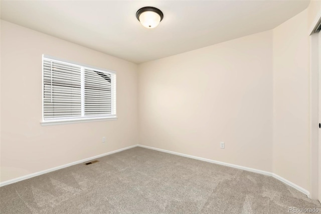 spare room with carpet floors, baseboards, and visible vents