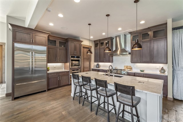 60 Barton Ridge Dr, Breckenridge, CO 80424 - kitchen with appliances with stainless steel finishes, wall chimney exhaust hood, dark brown cabinetry, decorative backsplash, and wood finished floors