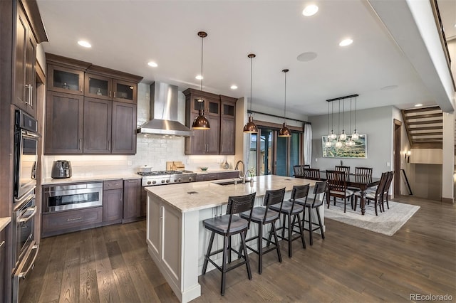 60 Barton Ridge Dr, Breckenridge, CO 80424 - kitchen with wall chimney range hood, stainless steel microwave, a kitchen bar, dark brown cabinetry, and dark wood-style floors
