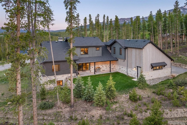 60 Barton Ridge Dr, Breckenridge, CO 80424 - rear view of house with stone siding, a yard, a shingled roof, a mountain view, and a chimney