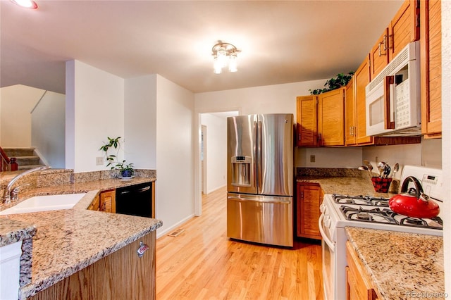 9614 W Powers Cir, Littleton, CO 80123 - kitchen with white appliances, light wood-style floors, brown cabinetry, and light stone countertops
