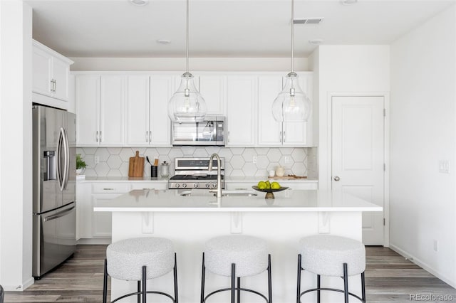 kitchen featuring light countertops, white cabinets, visible vents, stainless steel appliances, and wood finished floors