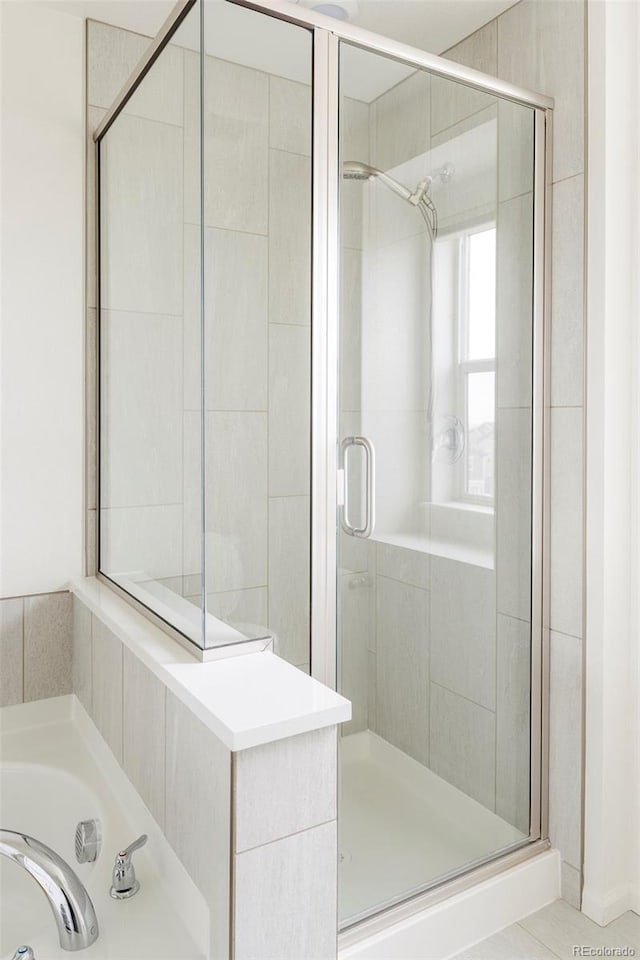 bathroom with a stall shower and a garden tub