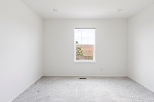 spare room featuring visible vents, baseboards, and light carpet