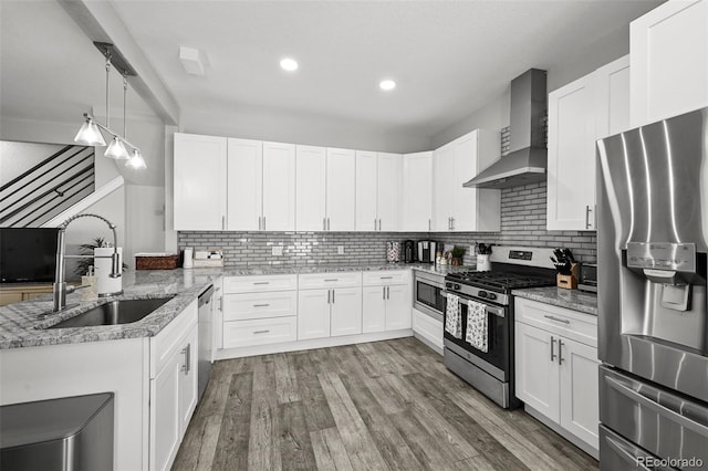 800 S Krameria St, Denver, CO 80224 - kitchen with stainless steel appliances, wall chimney exhaust hood, a sink, a peninsula, and decorative backsplash