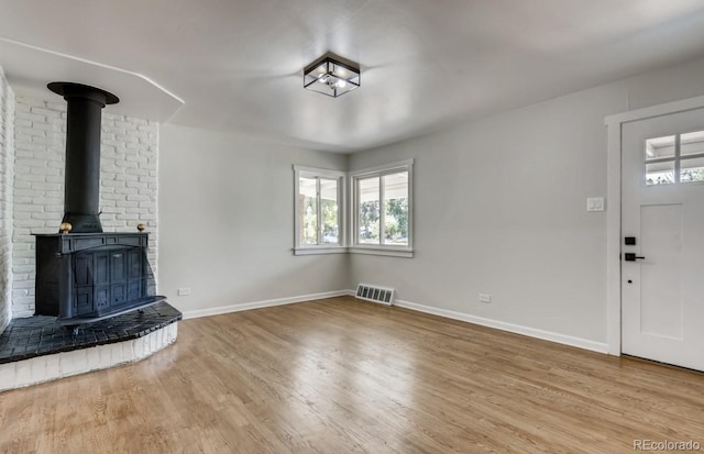 unfurnished living room featuring hardwood / wood-style floors and a wood stove