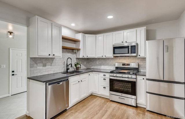 kitchen with white cabinetry, sink, stainless steel appliances, tasteful backsplash, and light hardwood / wood-style flooring