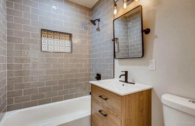 full bathroom featuring vanity, tiled shower / bath combo, and toilet