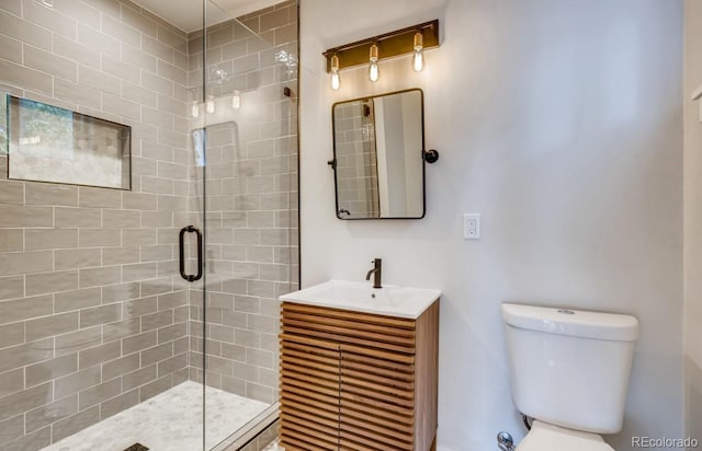 bathroom featuring vanity, toilet, and a shower with shower door