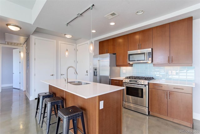 kitchen with decorative backsplash, sink, stainless steel appliances, and a kitchen island with sink