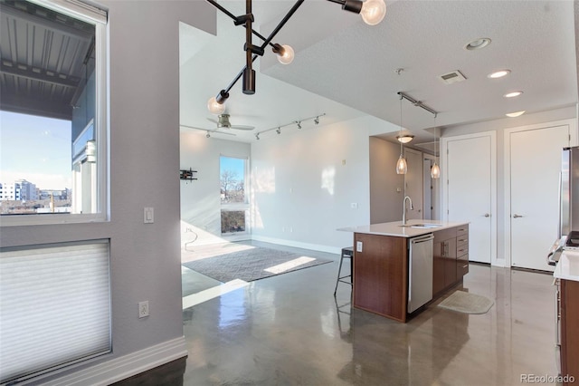 kitchen with stainless steel appliances, ceiling fan, sink, a breakfast bar area, and an island with sink