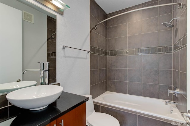 full bathroom featuring vanity, tiled shower / bath combo, and toilet