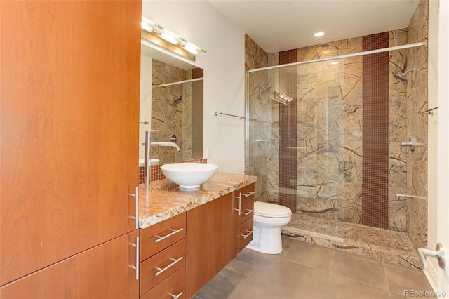 bathroom with tile patterned flooring, vanity, toilet, and a tile shower