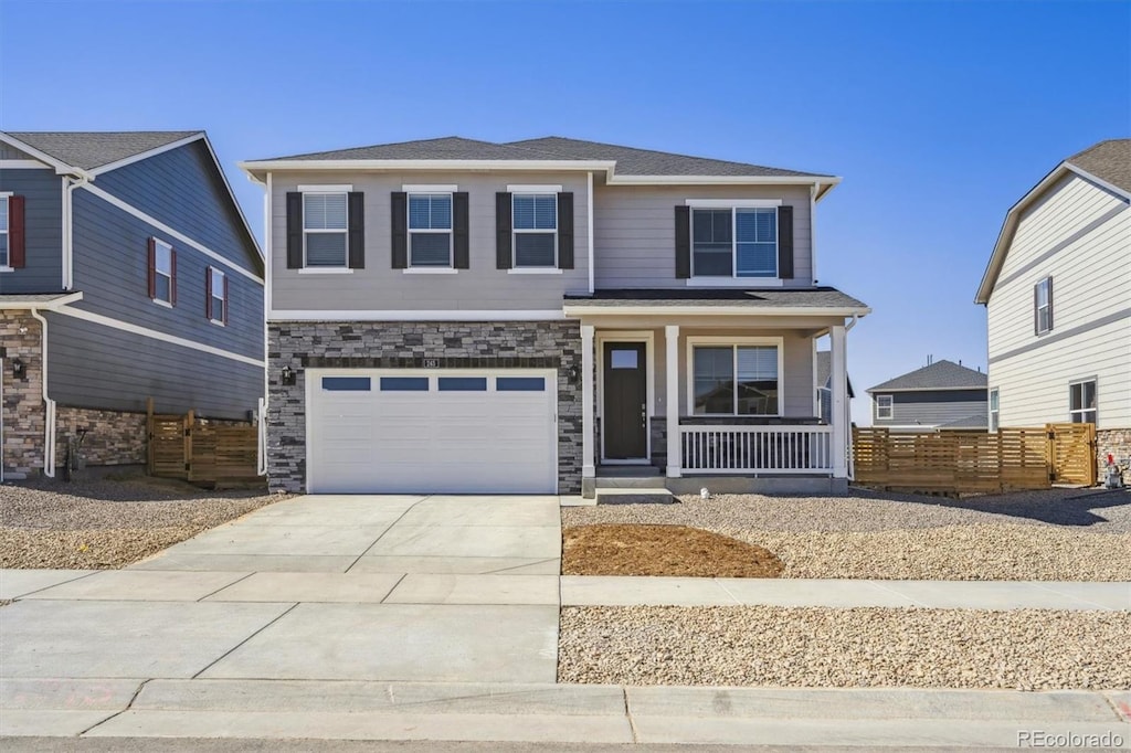 view of front of home with covered porch, fence, a garage, stone siding, and driveway