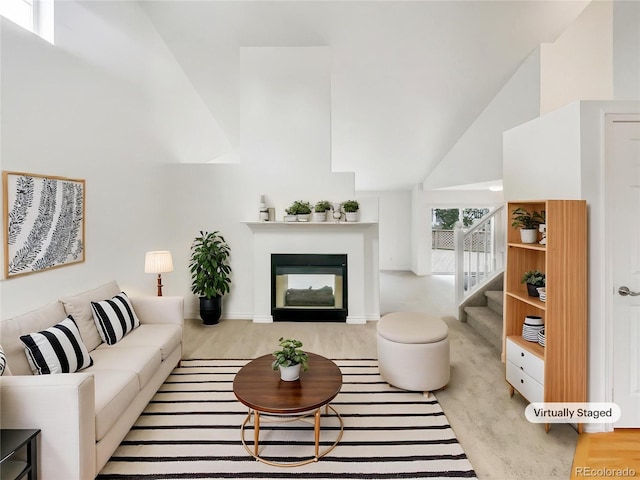 living room with high vaulted ceiling, stairway, and a glass covered fireplace