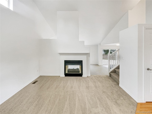 unfurnished living room with stairway, carpet flooring, baseboards, a multi sided fireplace, and a towering ceiling