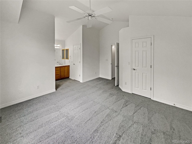 unfurnished bedroom featuring carpet, vaulted ceiling, baseboards, ensuite bath, and ceiling fan