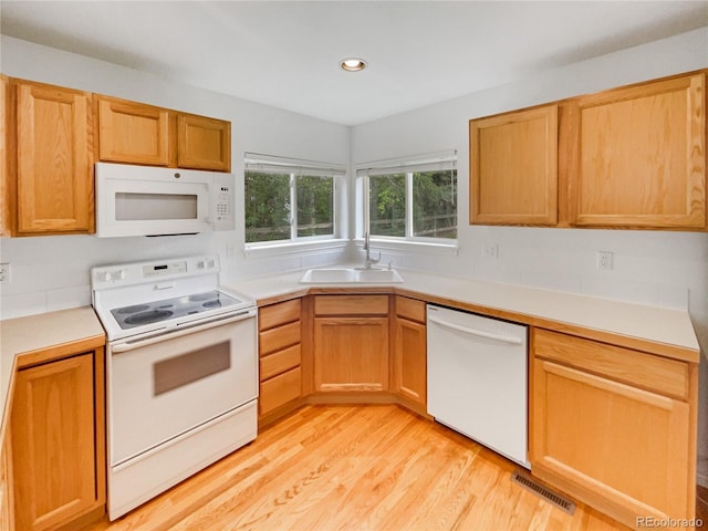 kitchen featuring white appliances, a sink, light wood-style flooring, light countertops, and recessed lighting