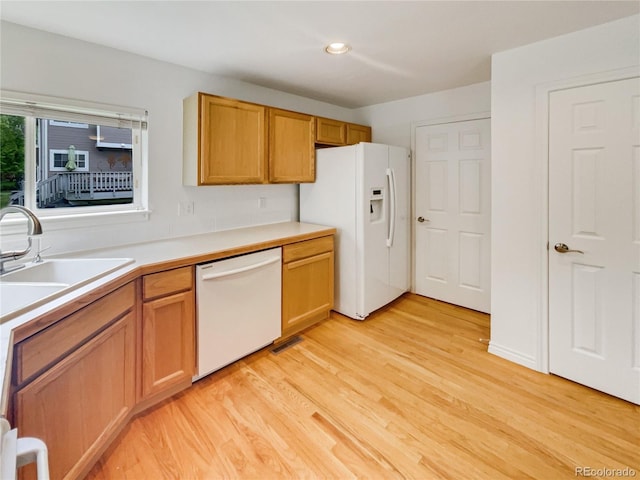 kitchen with white appliances, light wood-style floors, light countertops, recessed lighting, and a sink