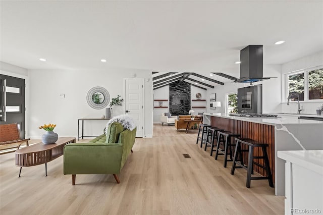 living room with lofted ceiling, sink, and light wood-type flooring