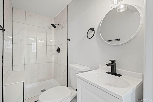 bathroom featuring vanity, toilet, and tiled shower