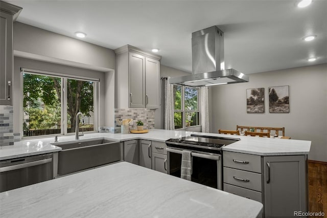 6285 Moccasin Pass Ct, Colorado Springs, CO 80919 - kitchen with gray cabinetry, island range hood, stainless steel appliances, decorative backsplash, and recessed lighting