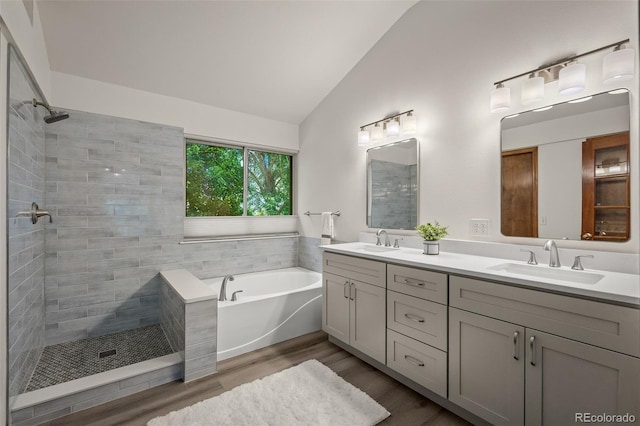 6285 Moccasin Pass Ct, Colorado Springs, CO 80919 - bathroom with lofted ceiling, a bath, double vanity, wood finished floors, and a tile shower