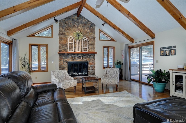 living room featuring a wealth of natural light, high vaulted ceiling, hardwood / wood-style floors, and a fireplace