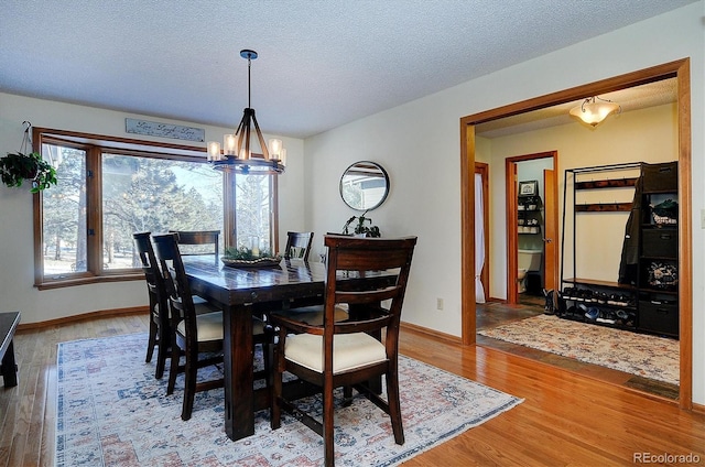 dining space featuring hardwood / wood-style flooring, a chandelier, and a textured ceiling