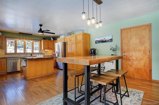 kitchen with hardwood / wood-style floors, decorative backsplash, stainless steel appliances, and a kitchen island