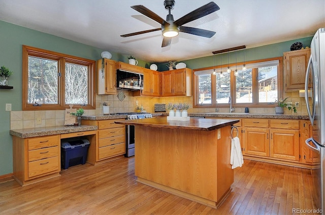 kitchen featuring a kitchen island, sink, light hardwood / wood-style floors, stainless steel appliances, and plenty of natural light