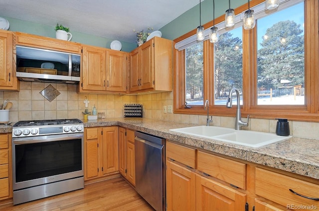 kitchen featuring appliances with stainless steel finishes, sink, backsplash, and light hardwood / wood-style floors