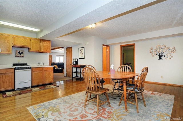 dining space with sink, a textured ceiling, and light hardwood / wood-style flooring