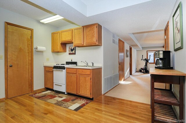 kitchen featuring white gas range, light hardwood / wood-style flooring, sink, and a textured ceiling