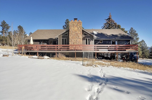 snow covered rear of property with a wooden deck