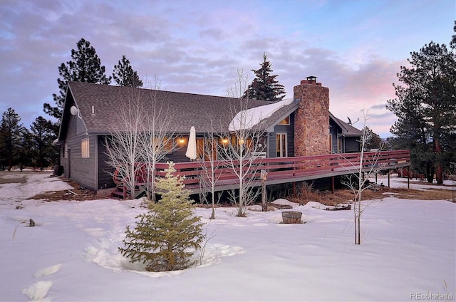 snow covered house with a deck and a fire pit