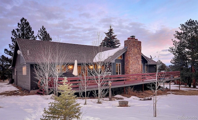 snow covered rear of property with a deck