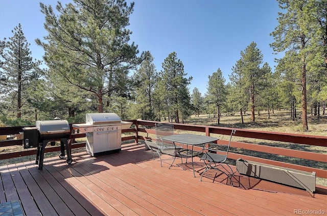 18360 Trail W Dr, Buena Vista, CO 81211 - wooden deck with outdoor dining space, grilling area, and view of wooded area