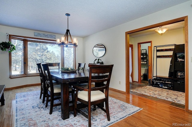 18360 Trail W Dr, Buena Vista, CO 81211 - dining space with wood finished floors, a chandelier, a textured ceiling, and baseboards