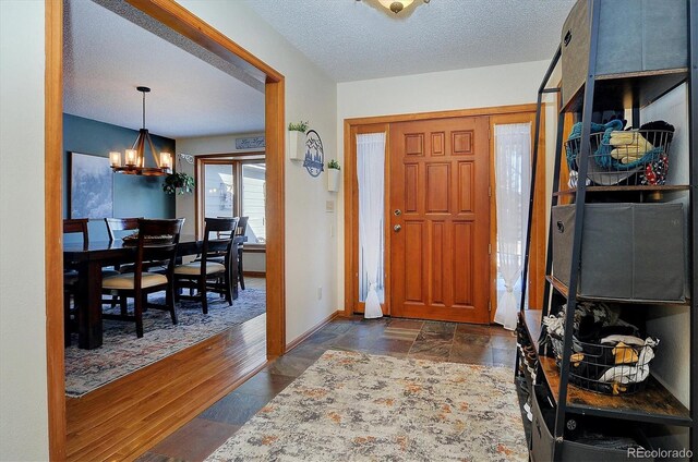 18360 Trail W Dr, Buena Vista, CO 81211 - foyer entrance featuring a chandelier, a textured ceiling, baseboards, and dark wood finished floors