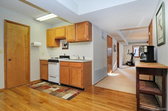 18360 Trail W Dr, Buena Vista, CO 81211 - kitchen with white gas range, light wood-type flooring, light countertops, a sink, and a textured ceiling