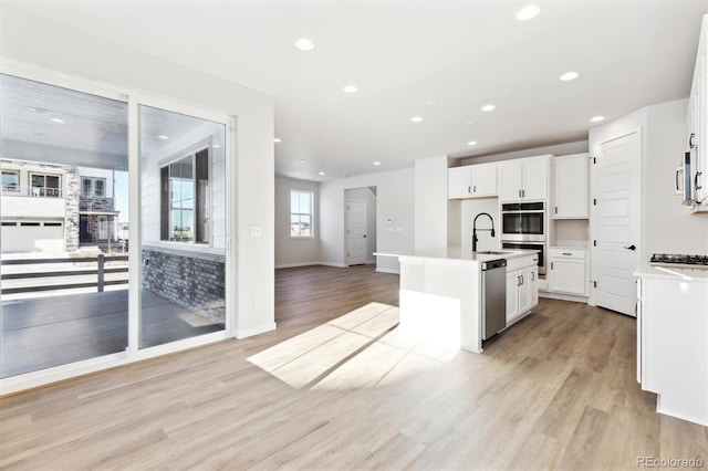 kitchen featuring appliances with stainless steel finishes, light hardwood / wood-style floors, a kitchen island with sink, and white cabinets