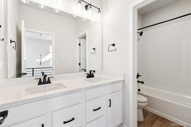 full bathroom featuring hardwood / wood-style flooring, vanity, toilet, and tiled shower / bath combo