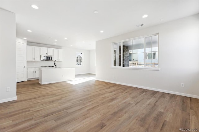 unfurnished living room featuring sink and light hardwood / wood-style floors