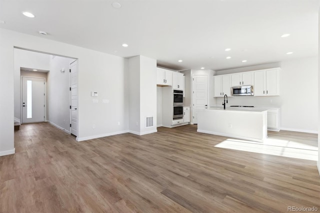 unfurnished living room with sink and light wood-type flooring