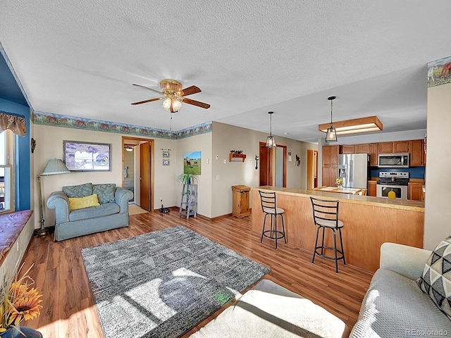 living room with ceiling fan, a textured ceiling, and light wood-type flooring