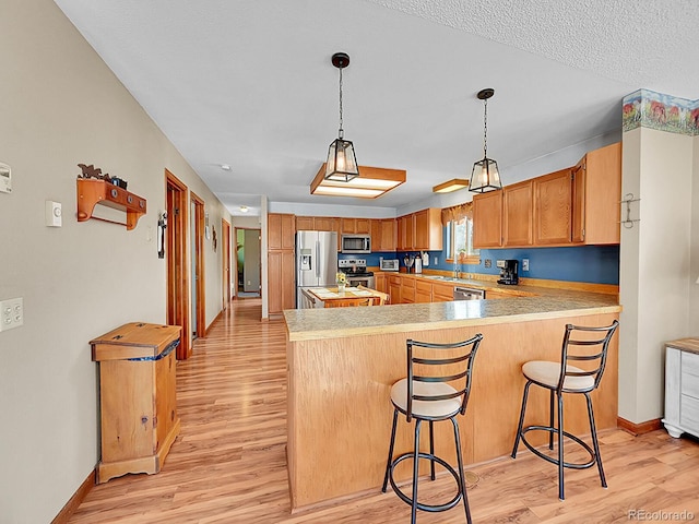 kitchen featuring appliances with stainless steel finishes, light hardwood / wood-style floors, a breakfast bar area, and sink