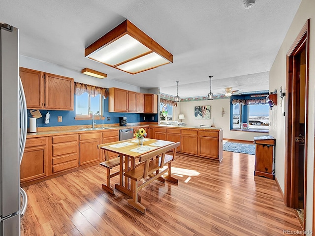 kitchen with kitchen peninsula, light wood-type flooring, decorative light fixtures, and sink